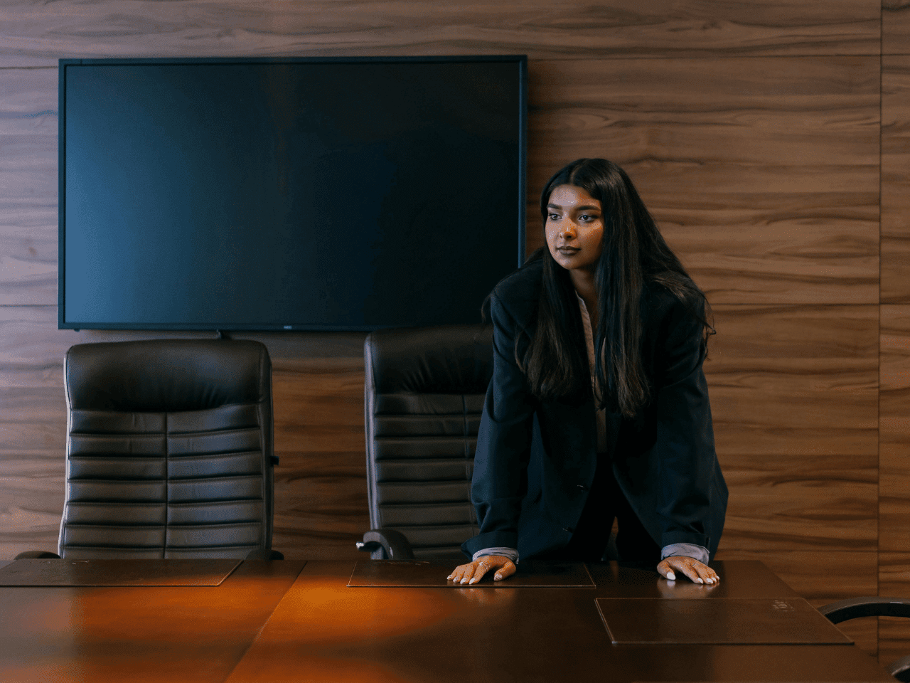 Strong, pensive leader leaning on desk in office setting